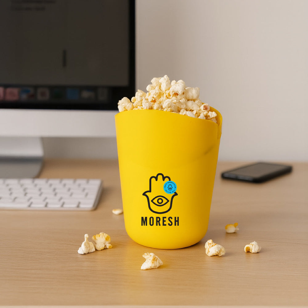 Moresh popcorn popper on a desk with popcorn scattered around.