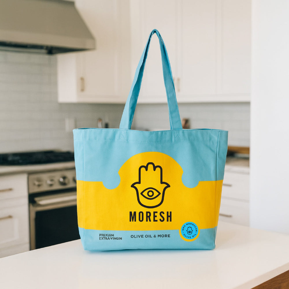 
                  
                    Moresh canvas tote bag in blue and yellow, made from eco-friendly fabric, displayed alone in a clean kitchen setting.
                  
                